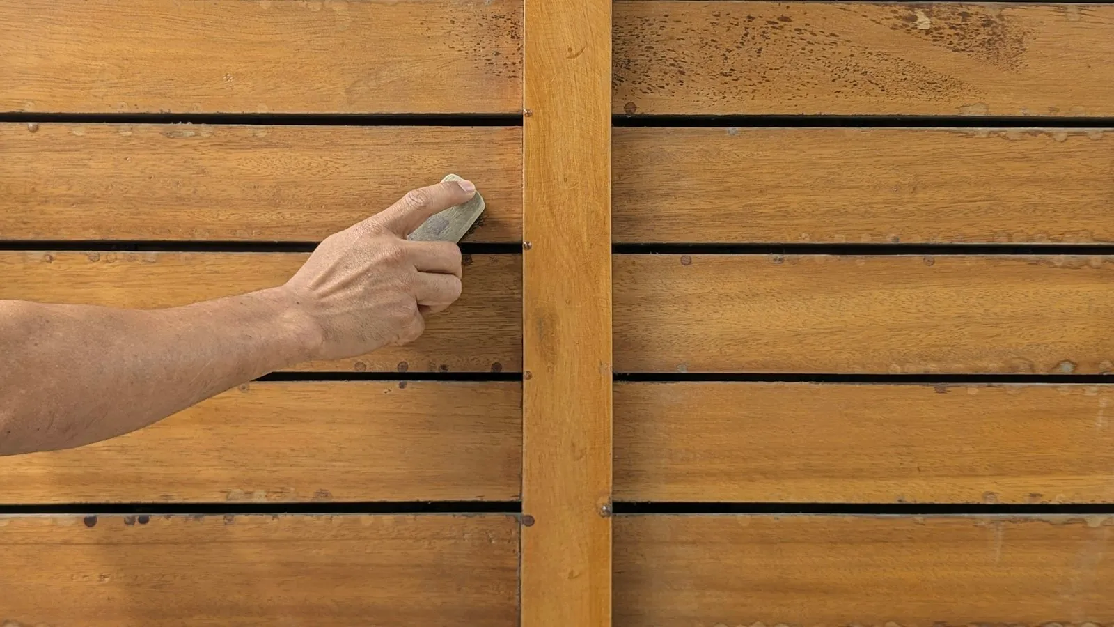 Hand schuurt een houten oppervlak glad