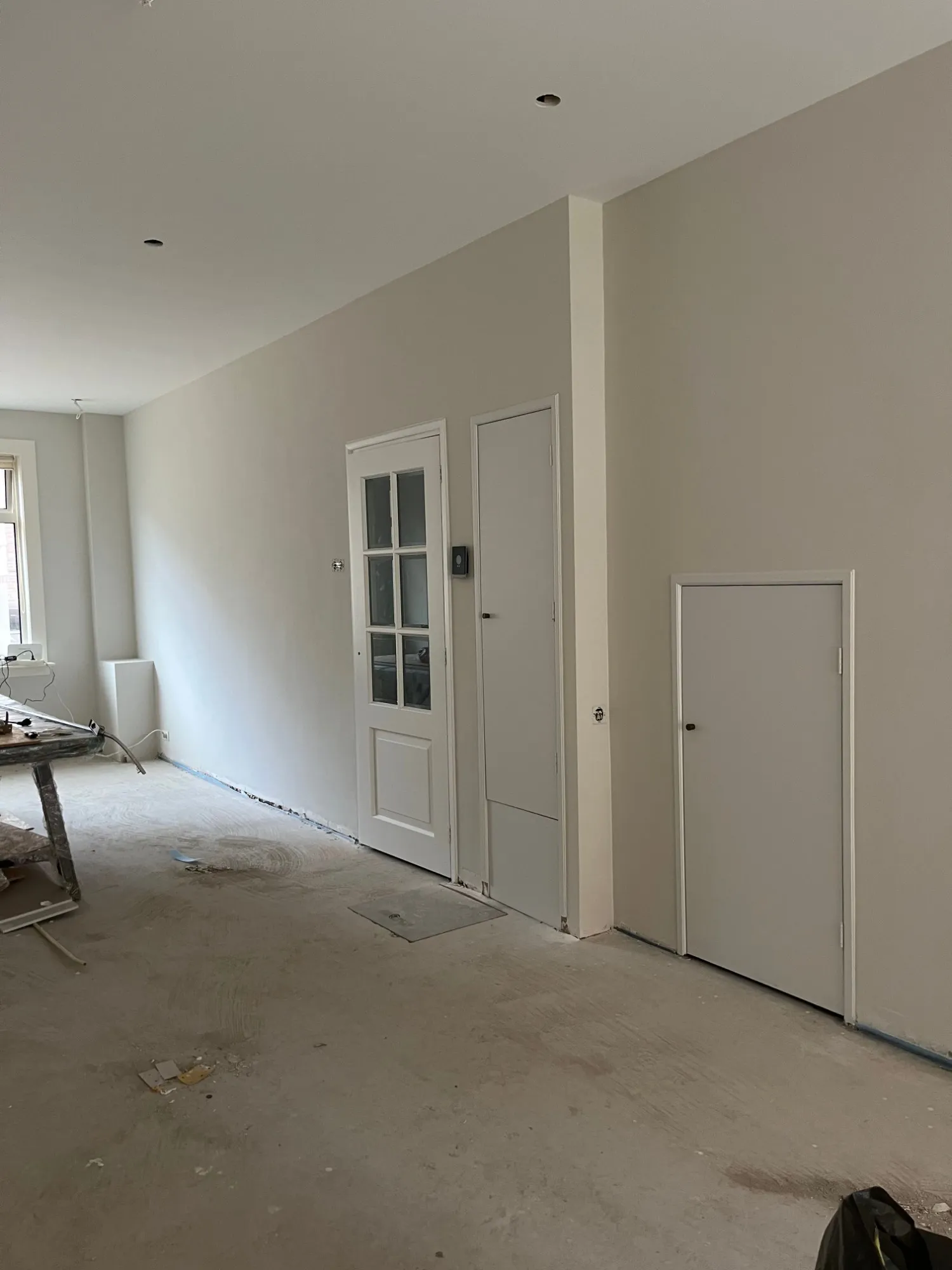 Strak geschilderde woonkamer met lichte wanden, witte deuren en kozijnen