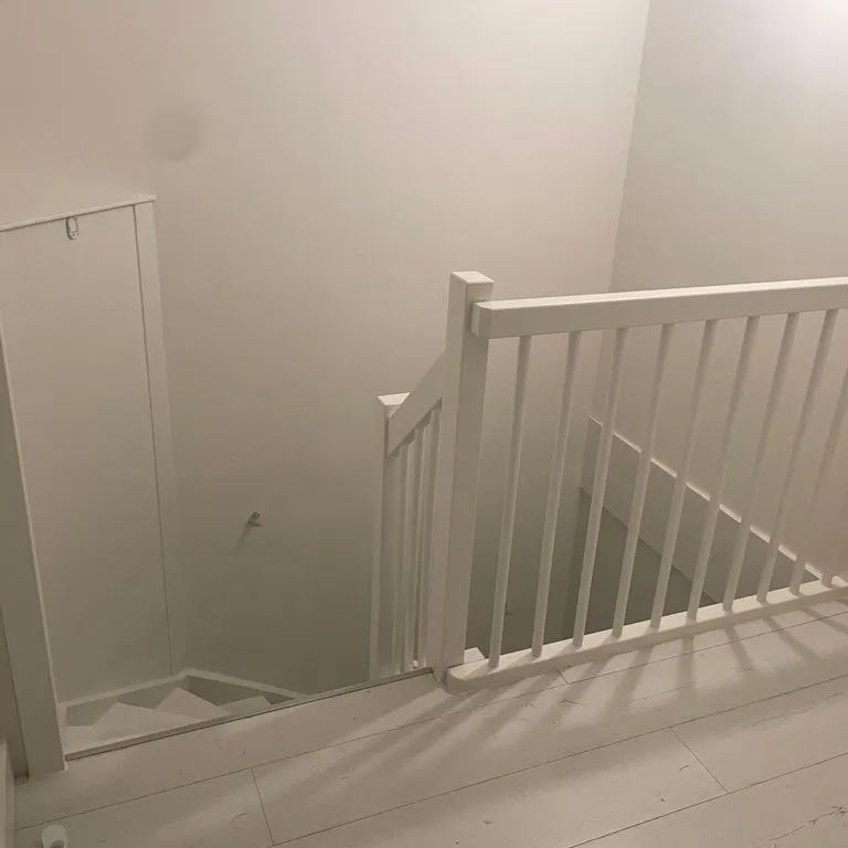 Wit geschilderde open trap met leuning, spijlen en balustrade op de overloop